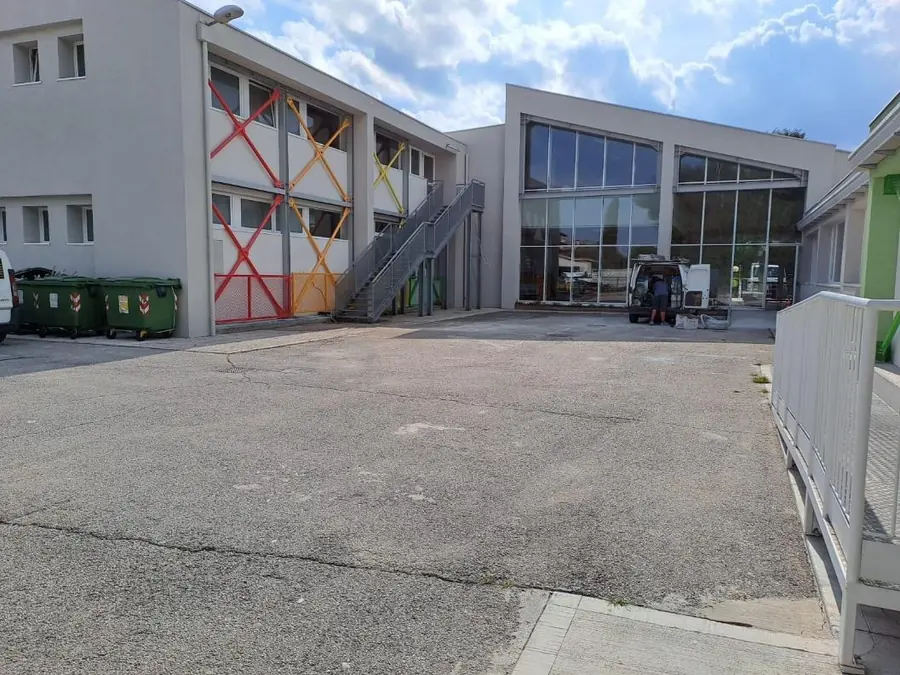 Edificio a due piani con controventi colorati in facciata e mezzo di lavoro davanti alle vetrate
